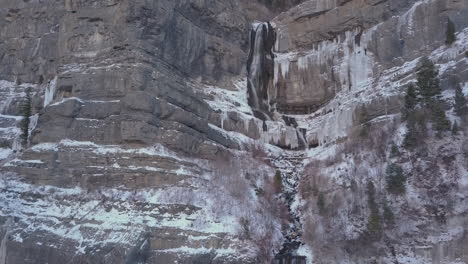 a beautiful waterfall half flowing and half frozen in rugged mountain terrain