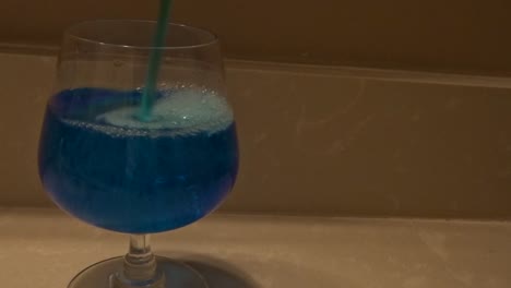 toma frontal de líquido azul que se vierte en una copa de vino.