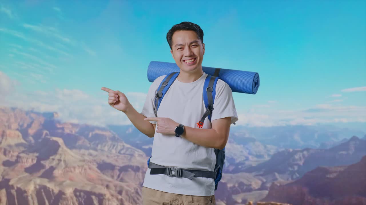 Asian Male Hiker With Mountaineering Backpack Smiling And Pointing To Side While Traveling At The Top Of Mountain