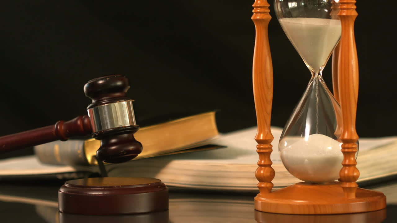 martillo cayendo en el bloque de sonido al lado de reloj de arena y la biblia