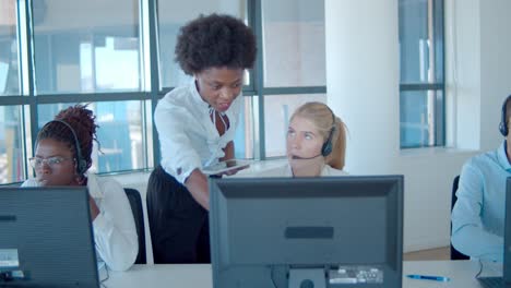 entrenador de centro de llamadas femenino serio que ayuda al operador en auriculares