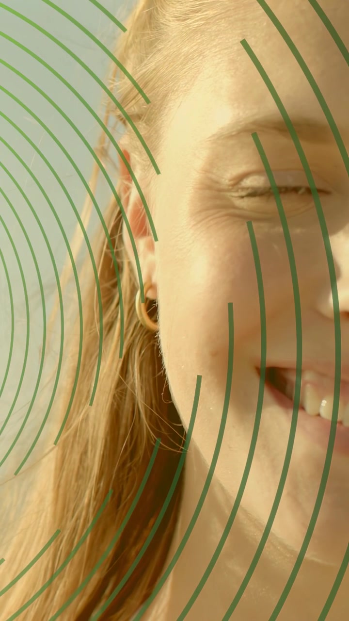 Vertical video: Woman turning smiling as sun lighting skin green curves over face in beauty