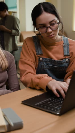young student focused on her laptop in a classroom setting