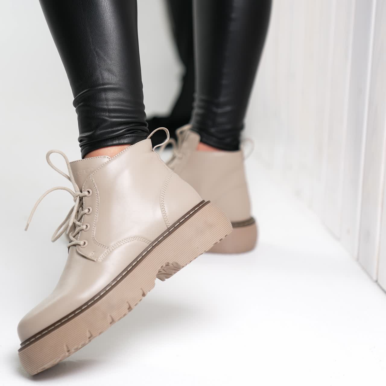 Presentation of beautiful modern beige low boots with laces. Stylish leather shoes on model at studio. Close up