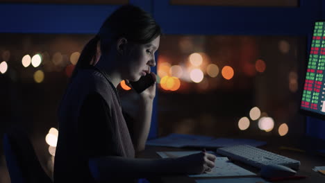 a female broker is talking on a mobile phone. portrait of a financial analyst working on computer with monitor workstation with real-time stocks commodities and exchange market charts