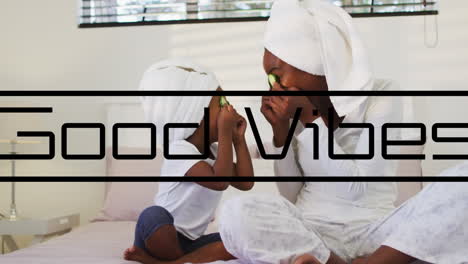 animation of good vibes text over african american mother and daughter playing in bathroom