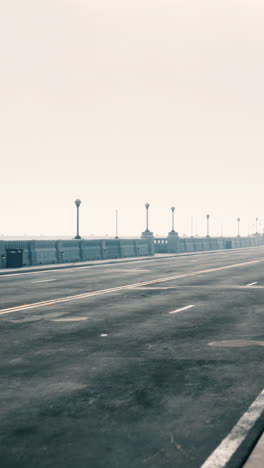 empty street with street lights on a bridge in the fog