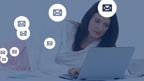 múltiples iconos de sobres flotando contra la mujer usando una computadora portátil