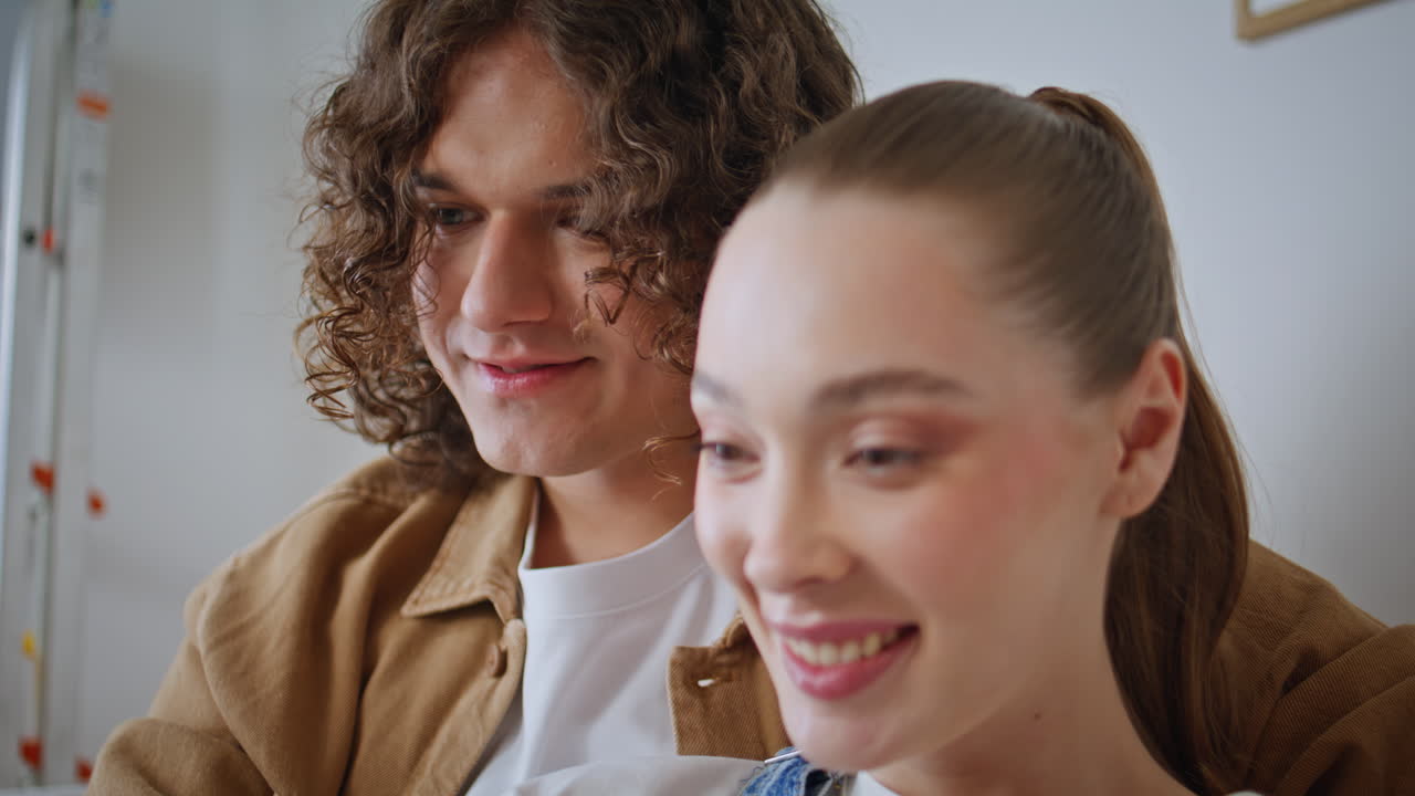 Portrait lovely couple watching something on laptop with excitement. Young woman