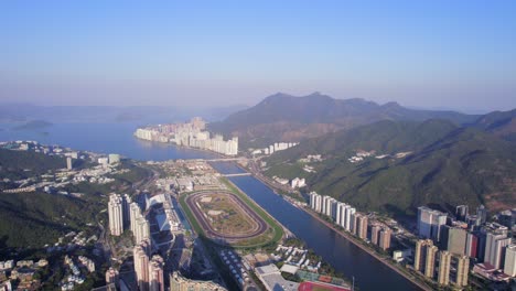 long shadows of the high-rise apartments stretch over the shatin racecourse which is located right next to the shing mun river