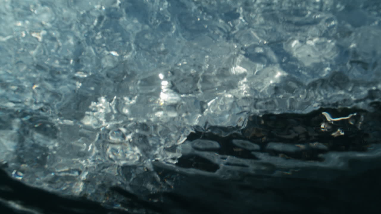 Slow motion inside of underwater barrel, dark vortex spinning below breaking wave face