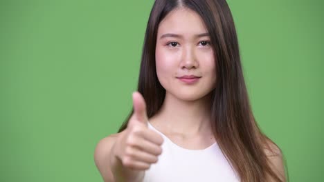 젊은 아름다운 아시아 사업가 여성이 엄지손가락을 올리고 있습니다.