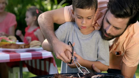 close up on a father is teaching to his son to do a barbecue