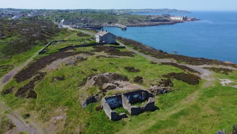 abandonado amlwch campo costero montaña casa vista aérea con vistas al puerto de anglesey aumento lento