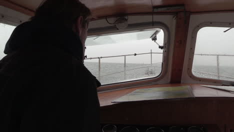 adult man steering a motorboat whilst looking at a nautical chart