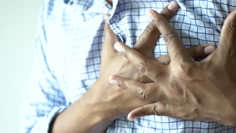 Joven sufre dolor en el corazón y sostiene el pecho con la mano