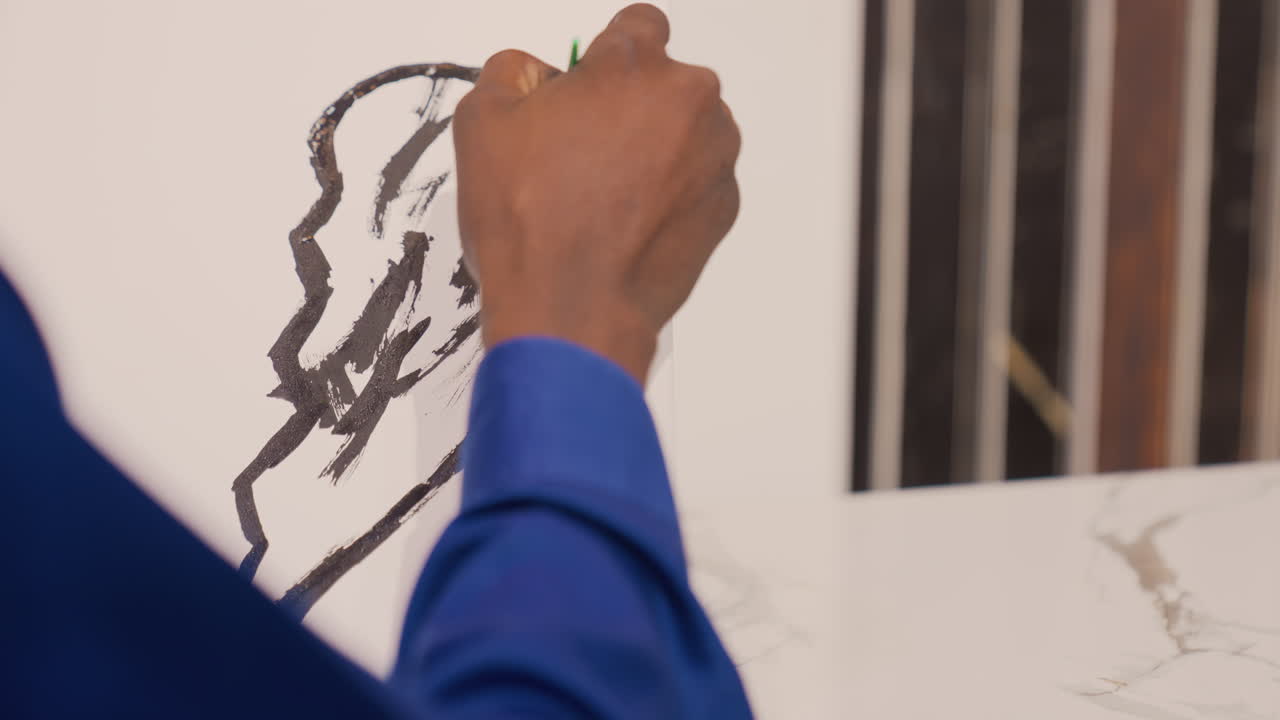 Dipinto nero su cavalletto, dettaglio finale di una mano che aggiunge delicate pennellate nere con una matita verde, silhouette raffinata di un orecchio, polsino blu, completamento sereno e composizione pronta per la galleria.