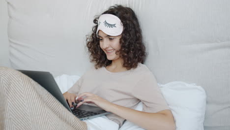 young woman working on laptop in bed