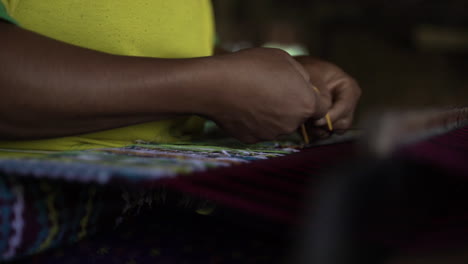 a lady in yellow shirt weaving traditional silk - close up