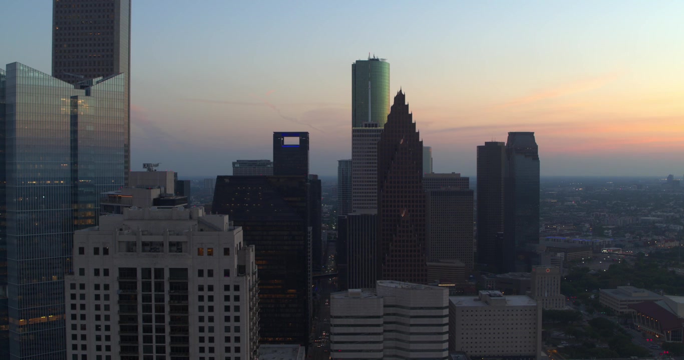 Vista aérea con dron del centro de Houston, Texas, mostrando modernos rascacielos y torres de oficinas durante el atardecer y la hora azul.