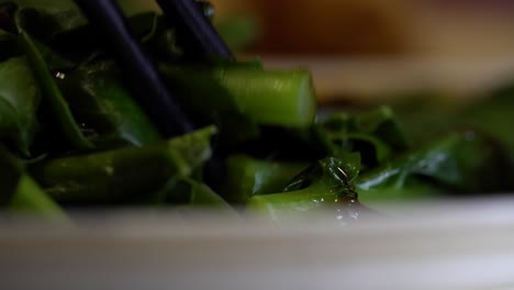 close-up shot of chopsticks picking up chinese sauteed greens