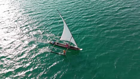 a small sailboat glides over turquoise ocean waters under a clear sky