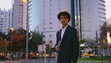 confident business man looking phone at sunset city. serious guy waiting street