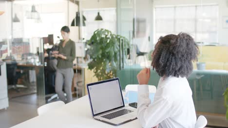biracial casual businesswoman in office making laptop video call, copy space on screen, slow motion