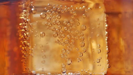 primer plano de burbujas en un cubo de hielo de soda naranja