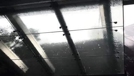 rain falling over hard glass roof ceiling of a modern structure