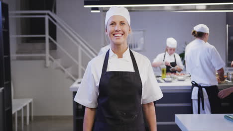 cocinera caucásica trabajando en la cocina de un restaurante mirando a la cámara y sonriendo