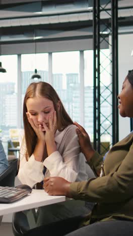 vertical video employee helping upset friend in need at work, comforting coworker
