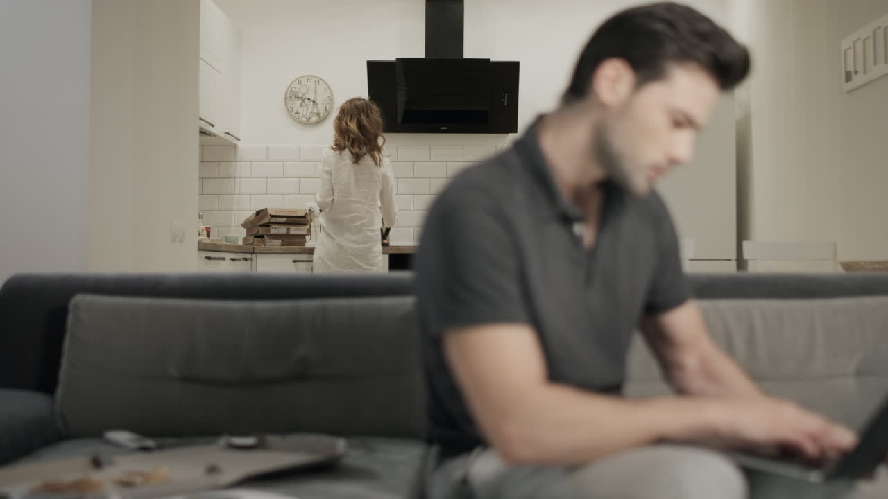 mujer poniendo hervidor en la cocina de la mañana bonita. hombre soñoliento cerrando cuaderno