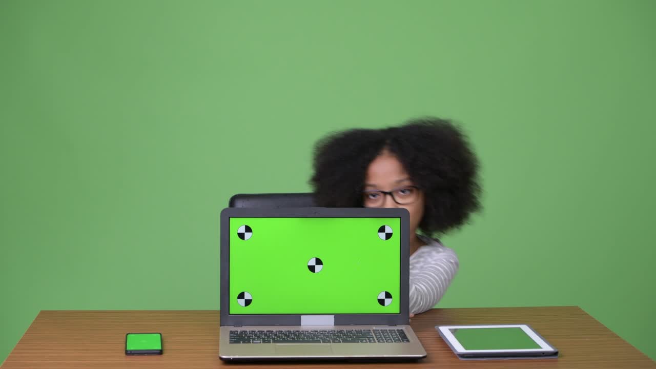 una joven africana con cabello afro que muestra una computadora portátil