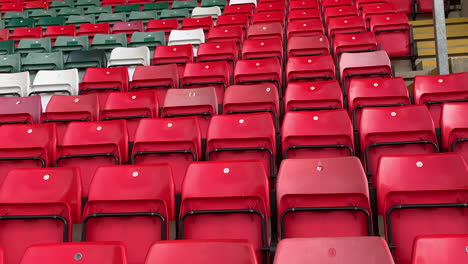 empty stadium stand with red green and which spectator seats in the sports grandstand