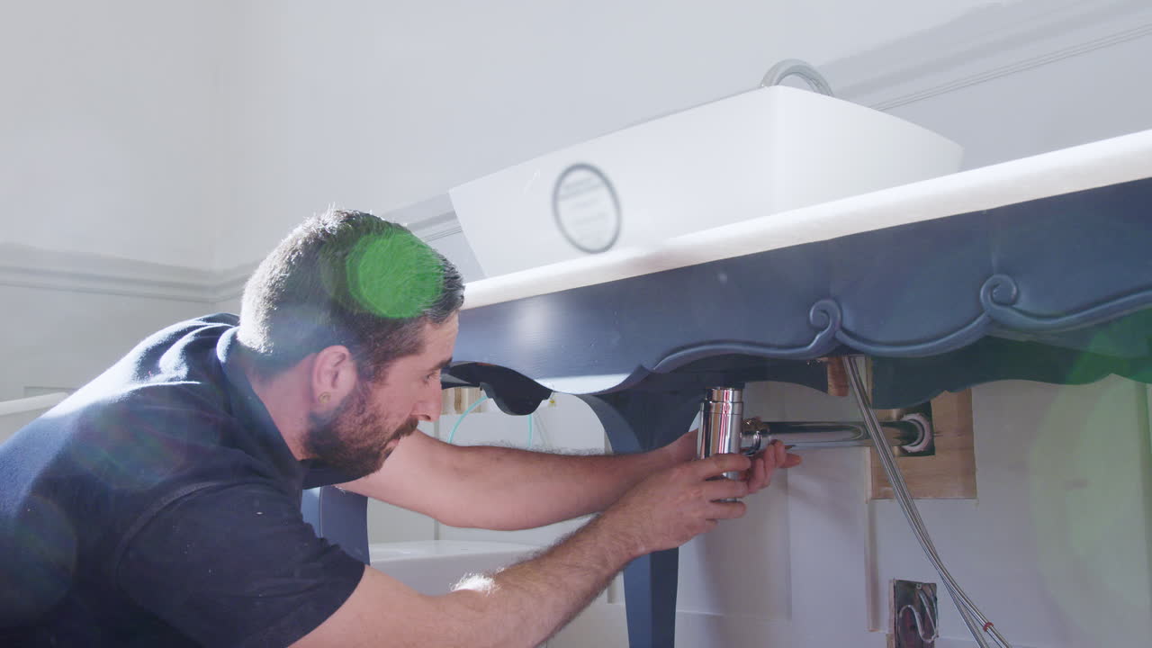 fontanero instalando una nueva trampa de residuos para lavar el lavabo en el baño