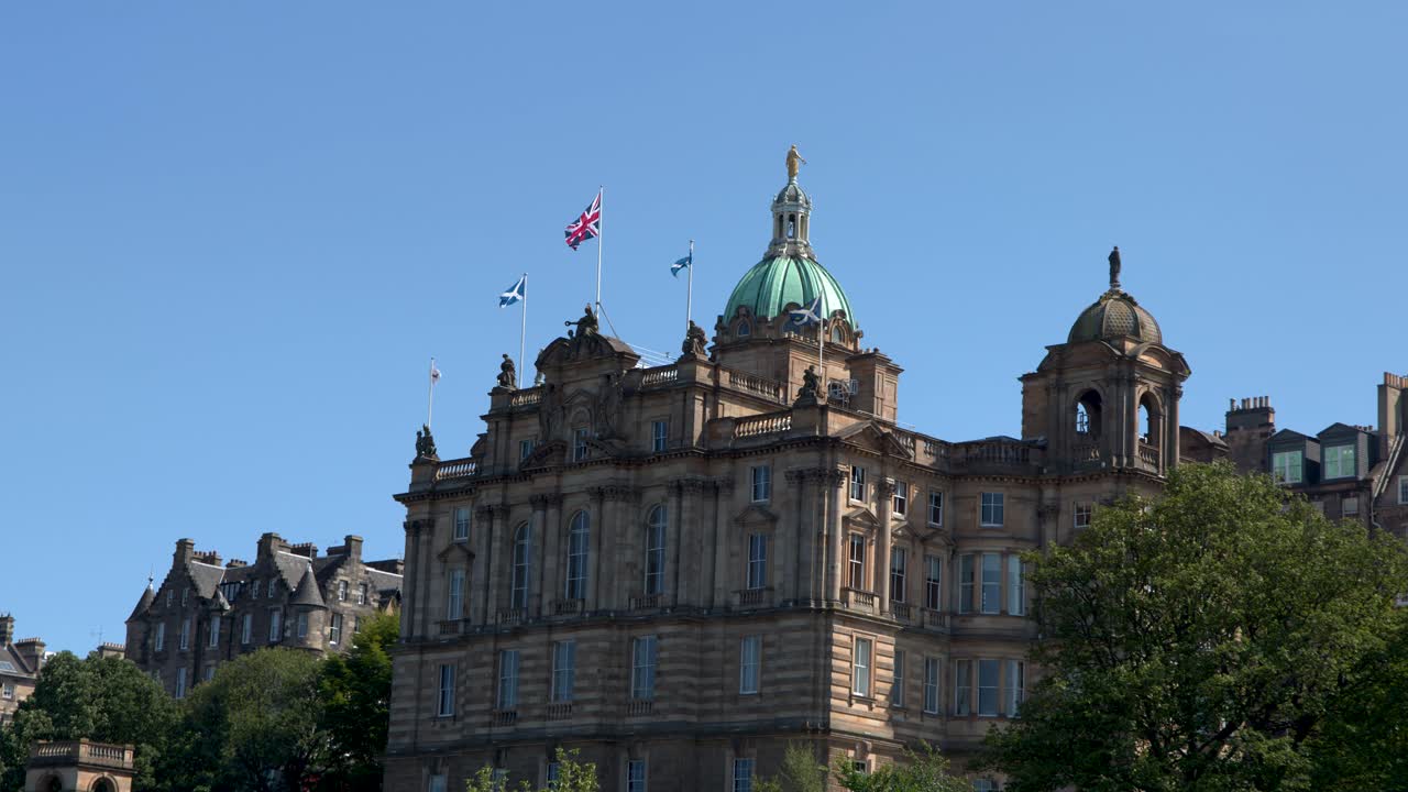 Camera slowly pans across classical stone building, green dome, flags, and clear blue sky