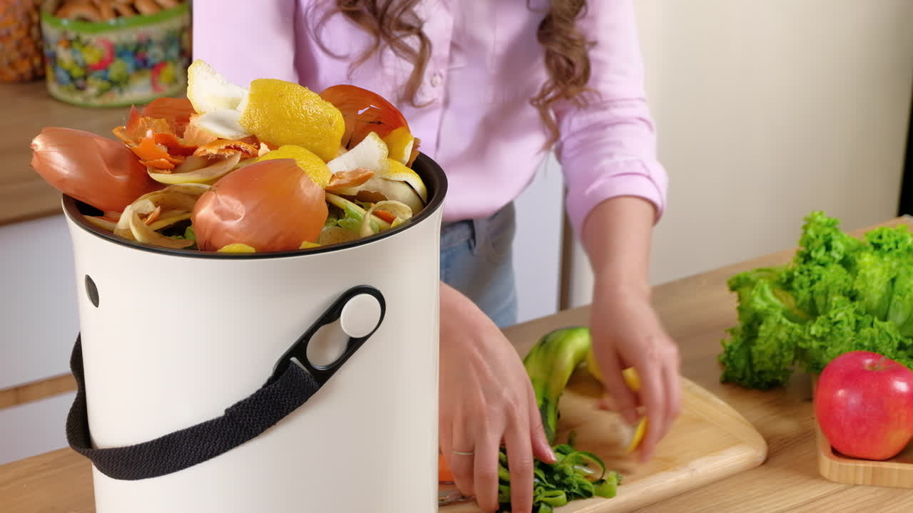Woman recycling organic waste by composting vegetables peels in the Bokashi in the kitchen