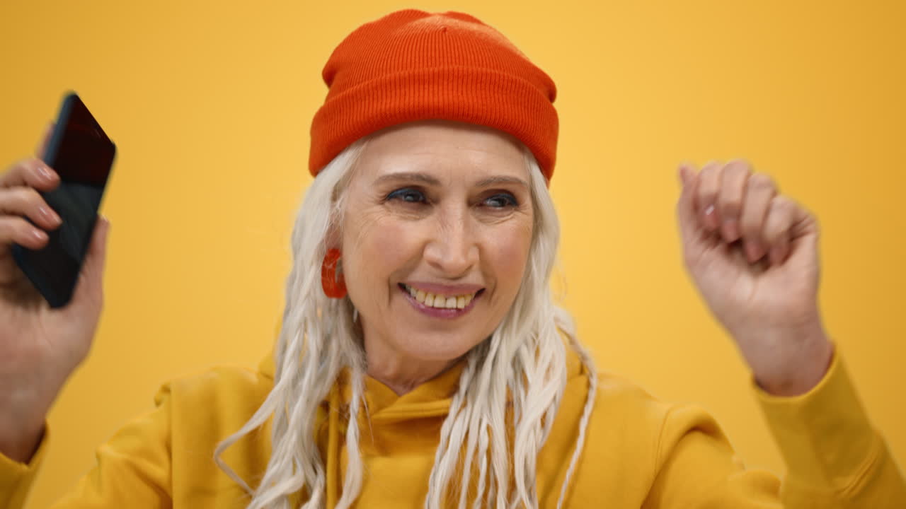 ⁇ 은 여성이 실내에서 전화로 음악을 듣고 있습니다. 스타일리시한 여성이 안에서 춤을 추고 있습니다.