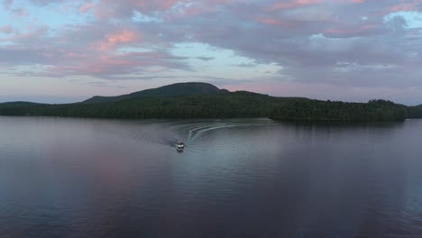 Toma-Aérea-Dando-La-Vuelta-A-Un-Barco-Solitario-En-Un-Hermoso-Lago-Con-Un-Cielo-Colorido-En-El-Municipio-Del-Este,-Quebec,-Canadá