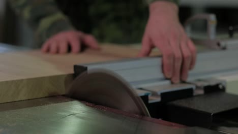 trabajador en camuflaje aserradura de madera en la máquina, aserrado de madera en un telar circular, el trabajo en el taller