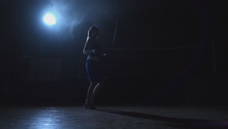 El-Plano-General-Del-Gimnasio-De-Boxeo-Con-Un-Ring-Y-Una-Joven-Hermosa-En-Pantalones-Cortos-Y-Una-Camiseta-Saltando-La-Cuerda.