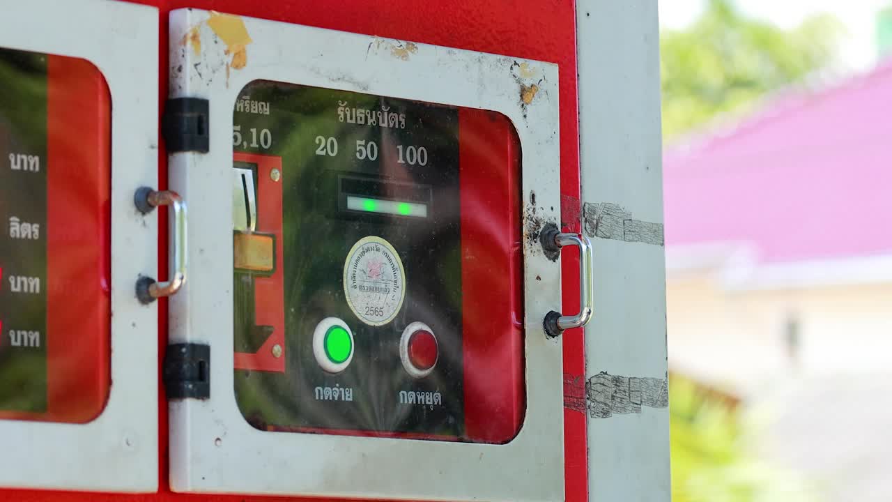 Person opens fuel vending machine door, interacts with payment panel in bright daylight, Phuket, Thailand