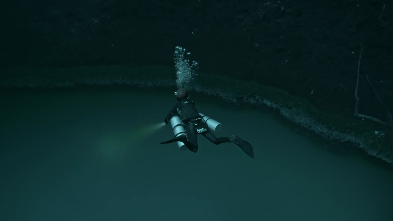 An ethereal image capturing a scuba diver descending toward the infamous hydrogen sulfide cloud layer of Cenote Angelita in the Yucatán