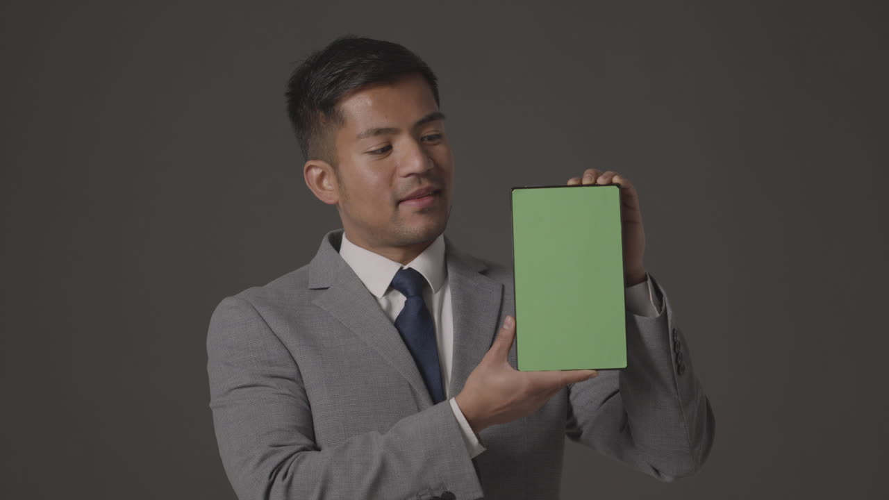 녹색 화면 디지털 태블릿을 들고 소송에서 웃는 사업가의 스튜디오 샷