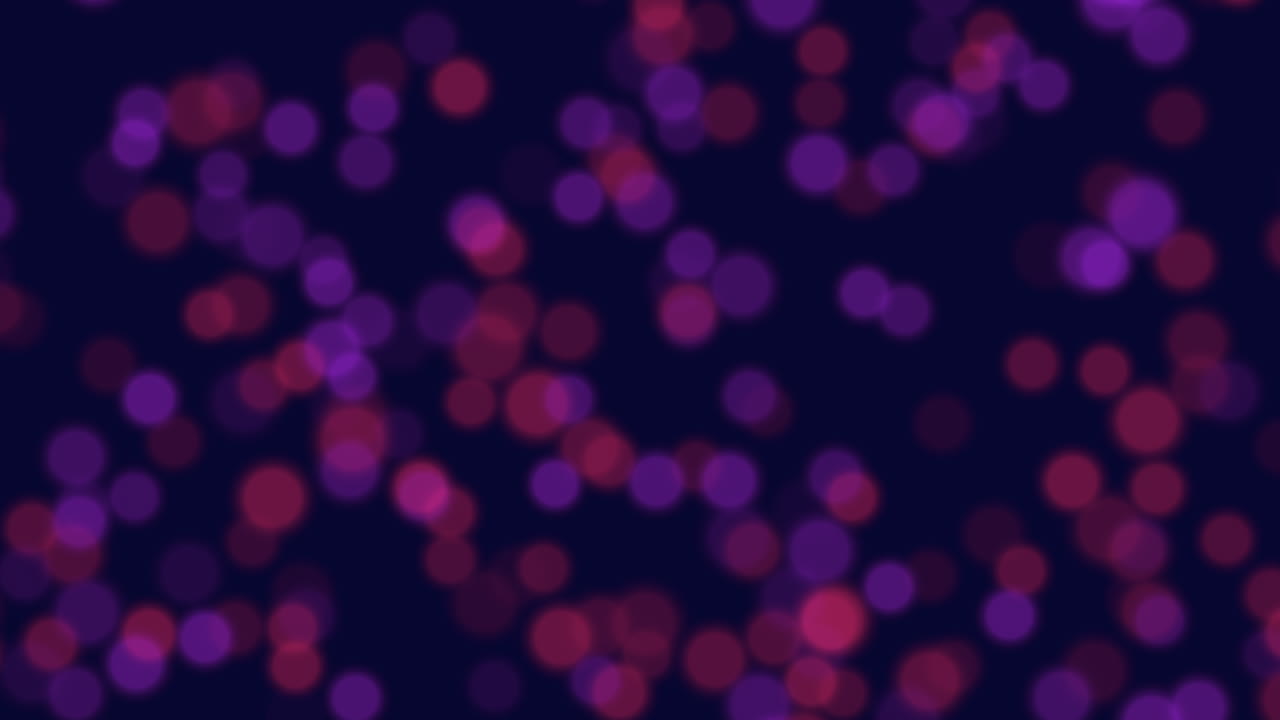 Circular pattern of purple and red dots in motion on a dark background. The vibrant colors and dynamic arrangement create a visually captivating display