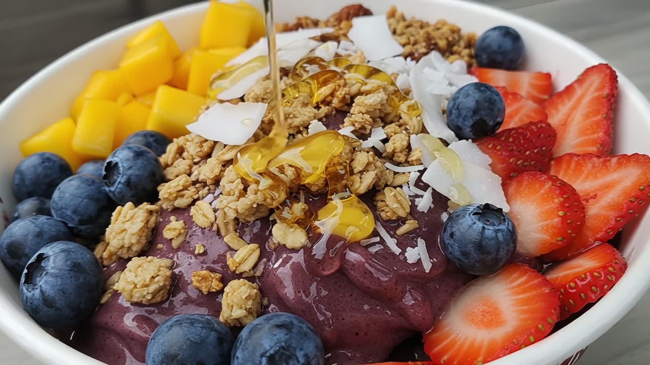 Colorful and Nutritious Smoothie Bowl Topped with Fresh Fruits, Granola, and Coconut Flakes, Drizzled with Honey for Added Sweetness and Flavorful Delight