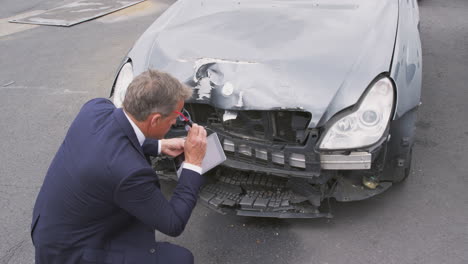 ajustador de pérdidas de seguros tomando una foto con una tableta digital de los daños al coche de un accidente automovilístico