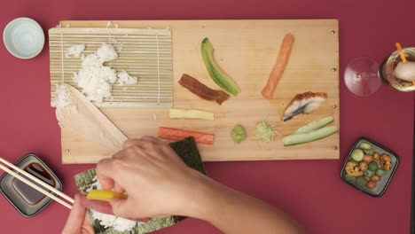 Top-shot-of-two-Hands-preparing-Sushi-on-red-table