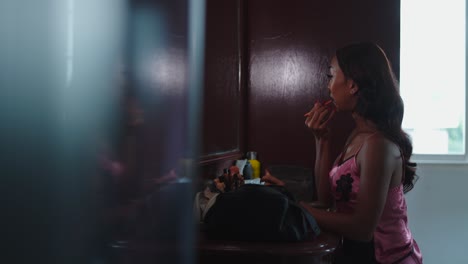 woman applying makeup in front of a mirror